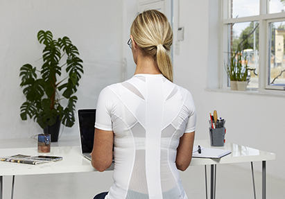Woman works by computer in white activeposture t-shirt